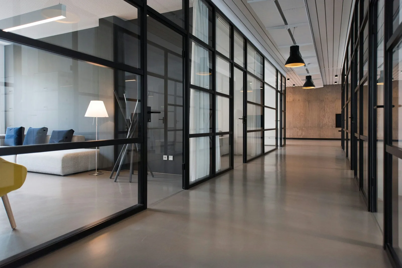 Illustrative office corridor with glass partitions and polished concrete floors
